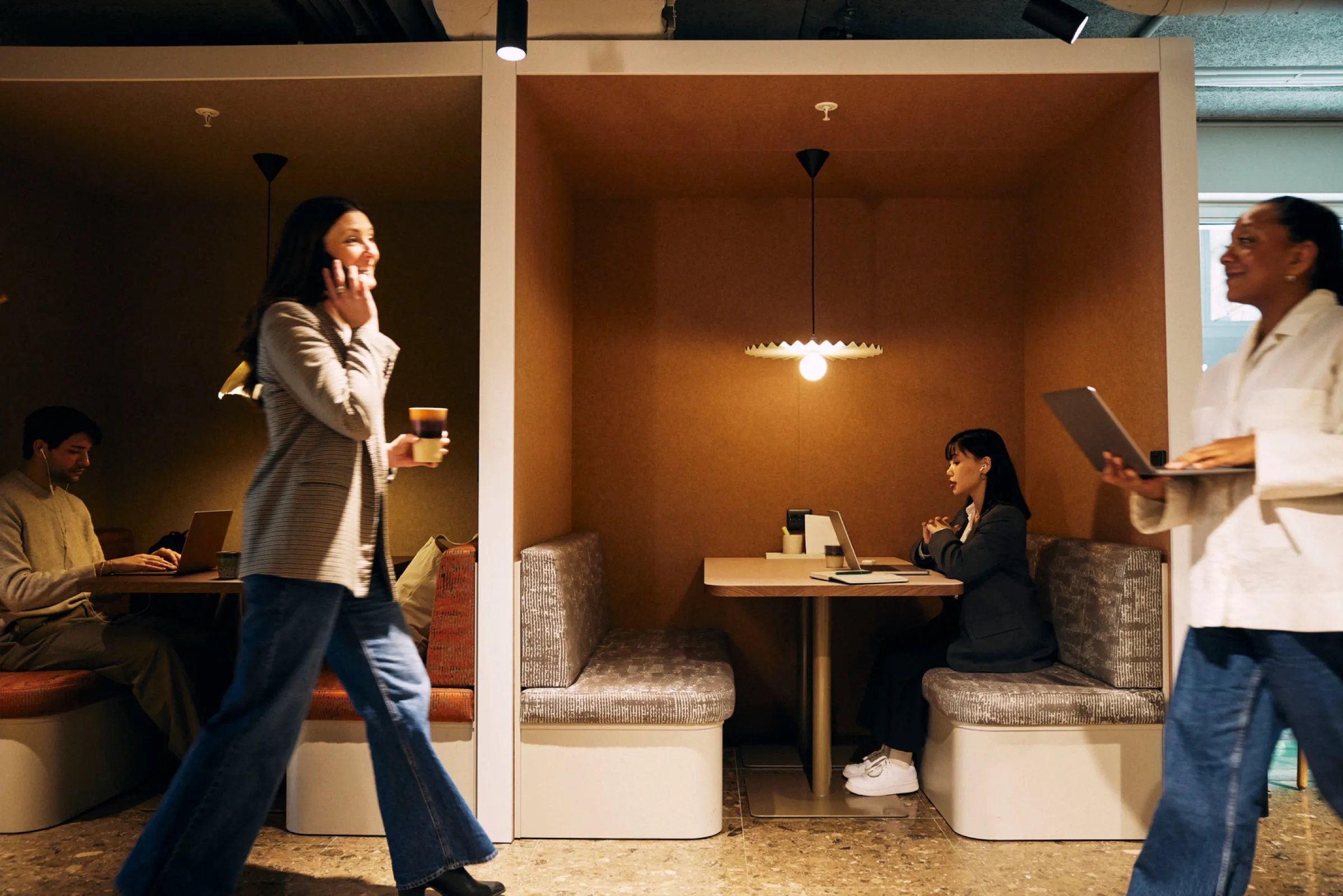 People walking past the booths in an open-plan office.
